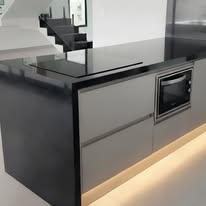 Ilha de cozinha com bancada preta, gavetões e iluminação inferior